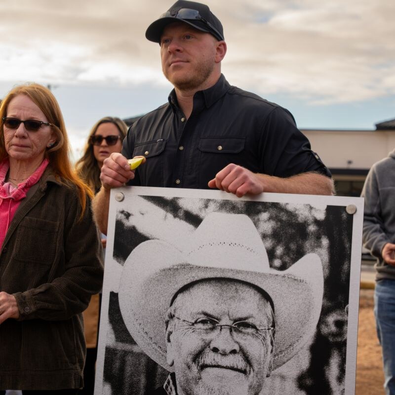 Jordon Snider holds a large portrait of his father Jimmy Snider at the Sticky Chikky Osage groundbreaking ceremony
