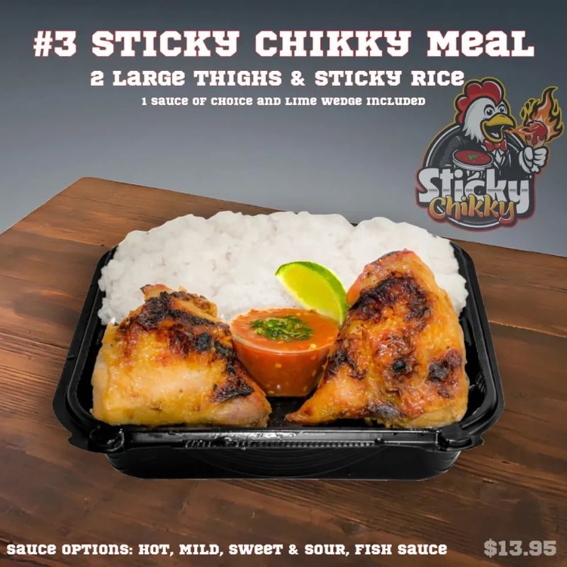 A black meal box with two thighs resting flat on sticky rice, a red sauce cup garnished with herbs, and a lime wedge