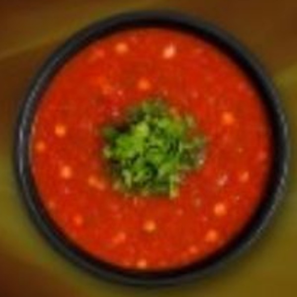 Vivid crimson sauce with green herb garnish in a matte black bowl