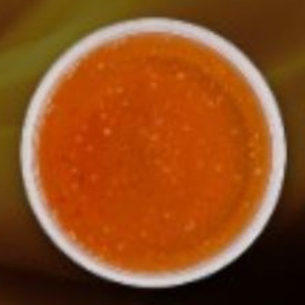 Amber-orange sauce with fine bubbly texture in a white bowl