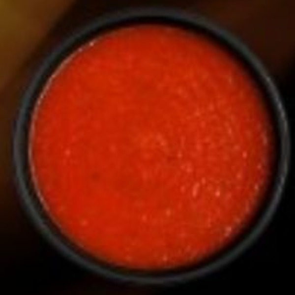 Vivid orange-red sauce in a dark bowl
