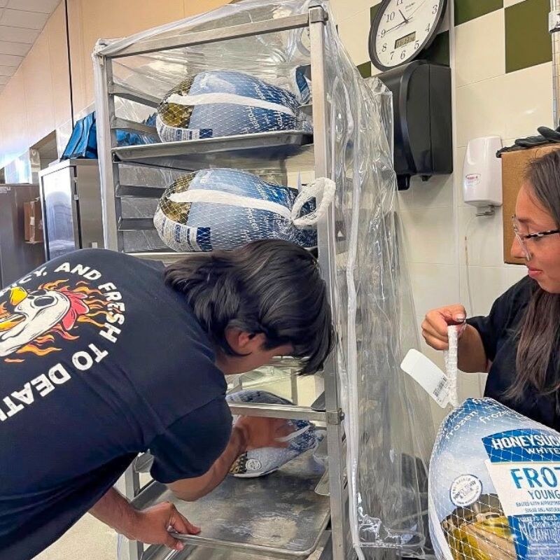 Sticky Chikky team members loading frozen turkeys onto a commercial rack during a Spirit Night food donation