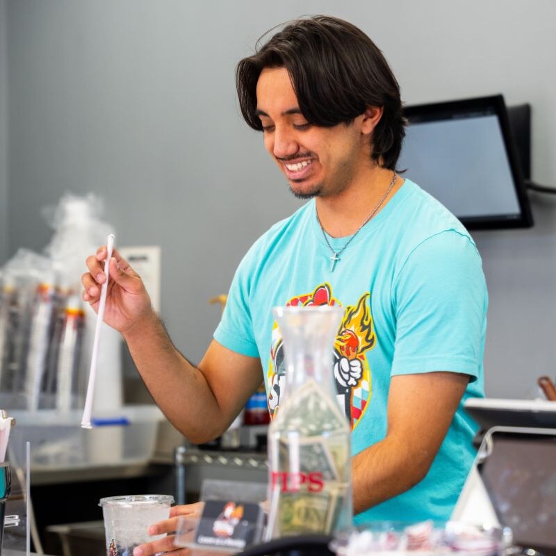 A smiling Sticky Chikky team member working the counter during a Spirit Night
